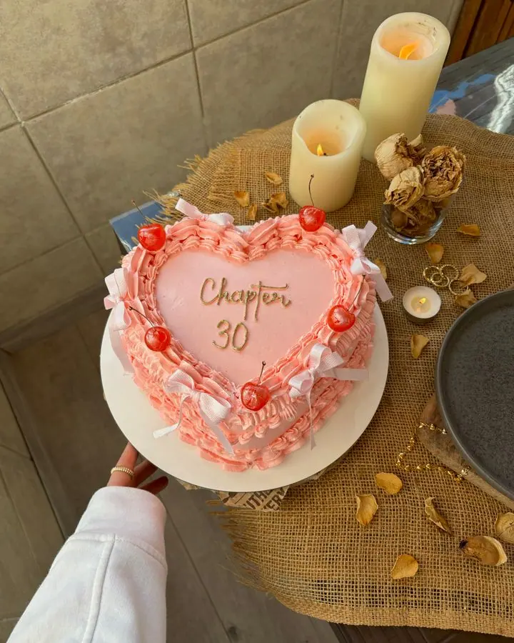Heart-shaped pink cream cake with cherries and piped borders