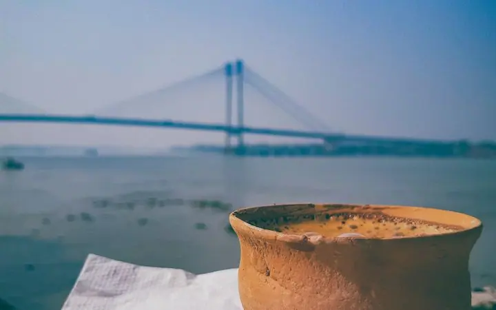 Clay cup of tea and jalebi on a ledge by the Hooghly, with the Vidyasagar Setu behind