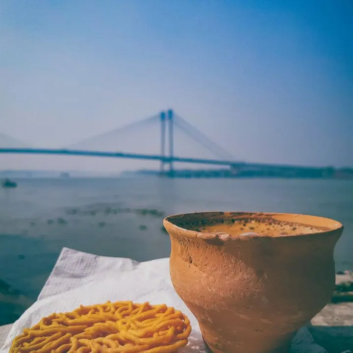 Clay cup of tea and jalebi beside the Hooghly with the Vidyasagar Setu in the distance, Kolkata