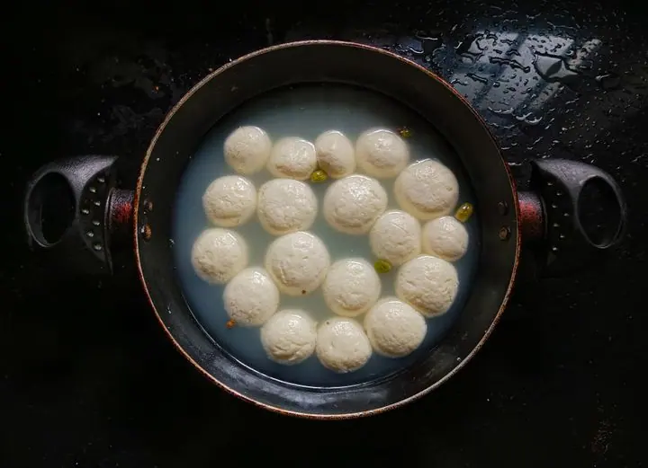 Rosogolla simmering in sugar syrup in a large pot, seen from above