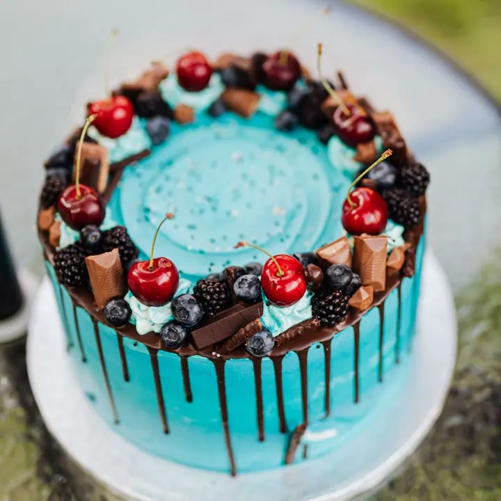 Blue drip cake topped with cherries and chocolate